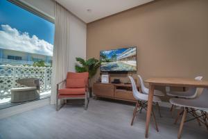 a living room with a table and chairs and a television at Luxury 1 bed apartment near Seven Mile Beach at The Grove - Villa Flamingo Haven in Upper Land