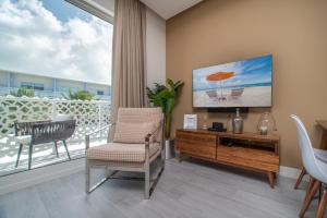 a living room with a balcony with a tv and a chair at Luxury 1 bed apartment near Seven Mile Beach at The Grove - Villa Gypsy Soul in Upper Land