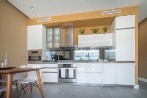 a kitchen with white cabinets and a wooden table at Luxury 1 bed apartment near Seven Mile Beach at The Grove - Villa Gypsy Soul in Upper Land