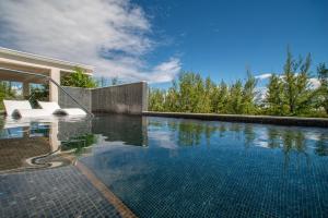 a swimming pool with two white chairs sitting next to a house at Luxury 1 bed apartment near Seven Mile Beach at The Grove - Villa Island Life in Upper Land