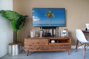 a tv sitting on top of a wooden entertainment center at Luxury 1 bed apartment near Seven Mile Beach at The Grove - Villa Nature Bliss in Upper Land