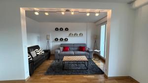 - un salon avec un canapé gris et des oreillers rouges dans l'établissement Superbe appartement en centre-ville, 20min de Paris, 5 min d'Enghien, à Saint-Gratien