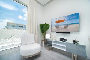 a living room with a white chair and a desk at Luxury 1 bed apartment near Seven Mile Beach at The Grove - Villa Deluxe in Upper Land