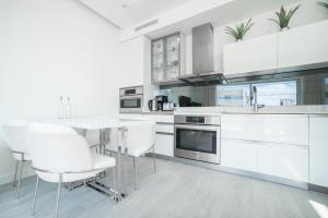 a kitchen with white cabinets and a table and chairs at Luxury 1 bed apartment near Seven Mile Beach at The Grove - Villa Deluxe in Upper Land