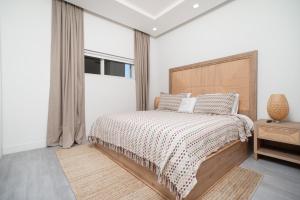a bedroom with a bed with a wooden headboard and a window at Luxury 1 bed apartment near Seven Mile Beach at The Grove - Villa Zen in Upper Land +42 photos