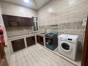 a kitchen with a washing machine and a washer at Aknan Al Saada in Salalah