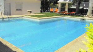 a large blue swimming pool with chairs and an umbrella at Villa Colmenar in Colmenar Viejo