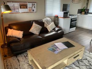 a living room with a leather couch and a coffee table at Anahita Studio in Balingup