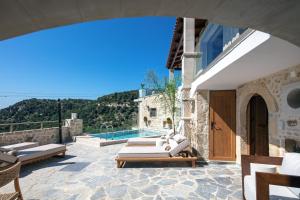 a patio with lounge chairs and a swimming pool at Moundros Luxury Villa & Spa in Moúndros