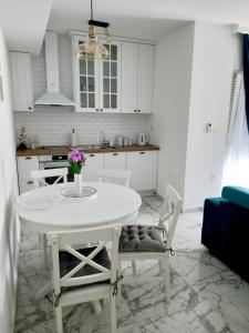 een witte keuken met een witte tafel en stoelen bij Amellia in Ljubuški