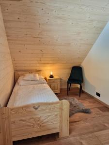 a bedroom with a bed and a chair in a attic at Babiogórska Chata - dom z bali z jacuzzi i sauną in Zawoja