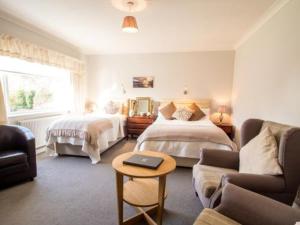 a bedroom with two beds and a couch and a table at The Coast Yard B & B and Garden Chalets in Chichester