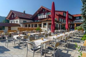 eine Reihe von Tischen und Stühlen mit roten Sonnenschirmen in der Unterkunft Hotel Natur-Landhaus Krone in Maierhöfen