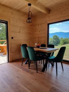 a dining room with a table and green chairs at Babiogórska Chata - dom z bali z jacuzzi i sauną in Zawoja