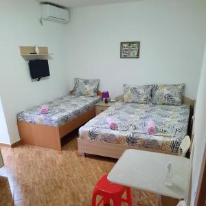 a bedroom with two beds and a table and a stool at Apartmani Milica Dojran in Star Dojran