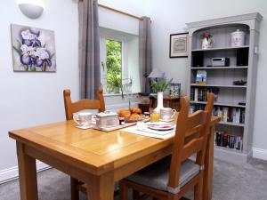 a wooden table in a room with a book shelf at Cosy Stone Cottage, The Bungalow Perrotts Brook in Cirencester