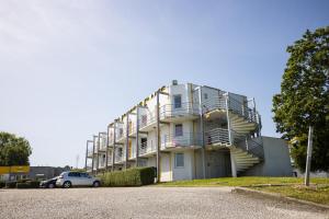 un bâtiment avec balcon et une voiture garée dans un parking dans l'établissement Première Classe Cherbourg - Tourlaville, à Cherbourg en Cotentin