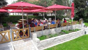 um grupo de pessoas sentadas em um restaurante sob guarda-chuvas em Hotel Natur-Landhaus Krone em Maierhöfen