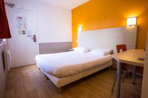 a bedroom with a bed and a table and a desk at Première Classe Cherbourg - Tourlaville in Cherbourg en Cotentin