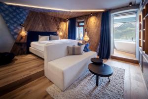 um quarto com uma cama, um sofá e uma janela em Boutiquehotel Blaue Burg Falkenstein em Pfronten