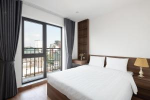 ein Schlafzimmer mit einem weißen Bett und einem großen Fenster in der Unterkunft Lakeside House 2 in Hanoi