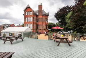 un grand bâtiment en briques avec des tables de pique-nique devant lui dans l'établissement Sefton Park Hotel, à Liverpool