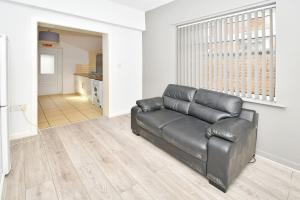 um sofá de couro preto sentado numa sala de estar em Townhouse @ 115 Walthall Street Crewe em Crewe