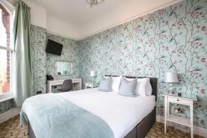 um quarto com uma cama e papel de parede floral em Sefton Park Hotel em Liverpool