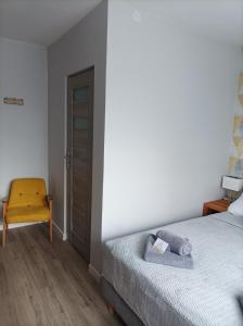 sypialnia z łóżkiem i żółtym krzesłem w obiekcie Słoneczna Dziesiątka w Solcu-Zdroju