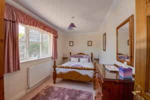 Schlafzimmer mit einem Bett, einem Schreibtisch und einem Spiegel in der Unterkunft Oak Tree Cottage, Charming, Rural New Forest Home in Boldre
