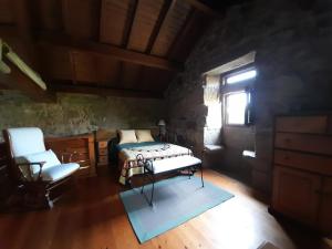 1 dormitorio con 1 cama, 1 silla y 1 ventana en A Casa da Gombra, en Villanueva de Arosa