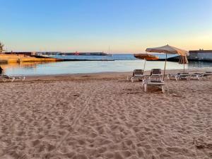 zwei Stühle und ein Sonnenschirm am Strand in der Unterkunft Ferienwohnung am Strand - 2 Schlafzimmer in Arguineguín