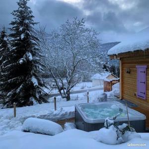 uma banheira de hidromassagem num quintal coberto de neve em Chalet L'Élégance - SPA - Serviettes - Peignoirs - Lits faits - Ménage inclus em Rochesson