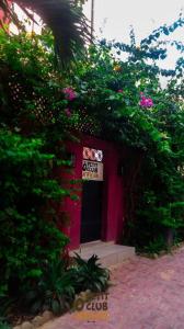un edificio rojo con una puerta y algunas flores en O Petit Club Africain Dakar en Dakar