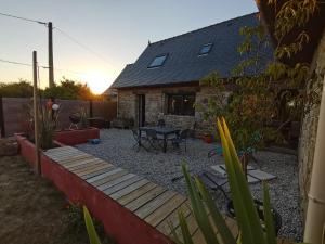 einen Hinterhof mit einer Holzterrasse und einem Tisch in der Unterkunft Belle maison en pierre in Cléder