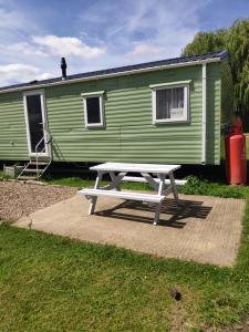 una mesa de picnic frente a un remolque verde en Lovely Static 6 Bed Caravan at Billing Aquadrome en Great Billing