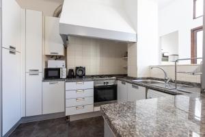 - une cuisine avec des placards blancs et des comptoirs en granit dans l'établissement Sleep in Centre - Aveiro, à Aveiro