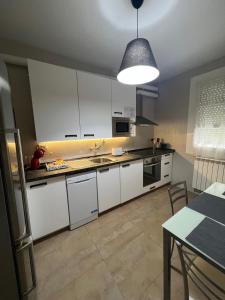 a kitchen with white cabinets and a table and aendant light at Apartamento Elena Tour in Logroño