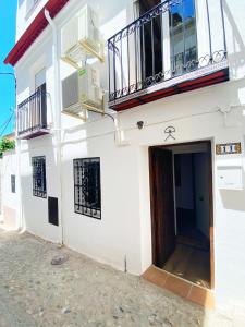Edificio blanco con puerta y balcón en Apartamentos Indalo a los pies del Albaicín, en Granada