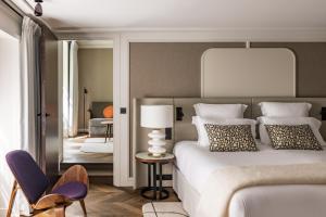 a bedroom with a bed and a chair and a mirror at Pavillon Faubourg Saint-Germain & Spa in Paris