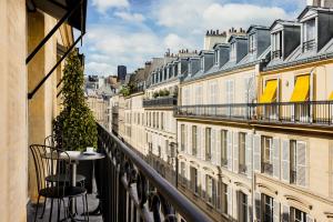 - un balcon avec une table, des chaises et des bâtiments dans l'établissement Pavillon Faubourg Saint-Germain & Spa, à Paris