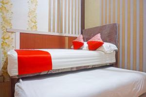 Una cama con almohadas rojas y blancas. en OYO 91433 Hotel Sari Jeneponto en Jeneponto