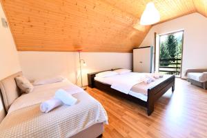 two beds in a room with wooden ceilings at Mate i Jaga in Saborsko
