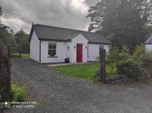 una pequeña casa blanca con una puerta roja en The Wild Farm Lodge, en Mullingar