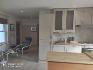 a kitchen with white cabinets and a table and a chair at The Wild Farm Lodge in Mullingar