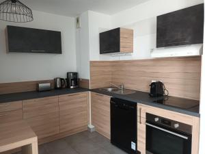 a kitchen with wooden cabinets and a sink at Superbe appartement et Parking proche du Centre du Monde in Perpignan