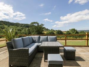 a wicker sofa and a table on a patio at The Old Kennels in Sidmouth