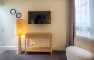 a room with a table with a lamp and a tv at Makom Pereire in Paris