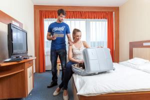 a man and a woman in a room with a suitcase at Hotel Lázně Kostelec in Zlín