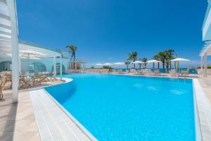 ein großer Pool mit Stühlen und Sonnenschirmen auf einem Gebäude in der Unterkunft Donnarumma Hotel in Casal Velino